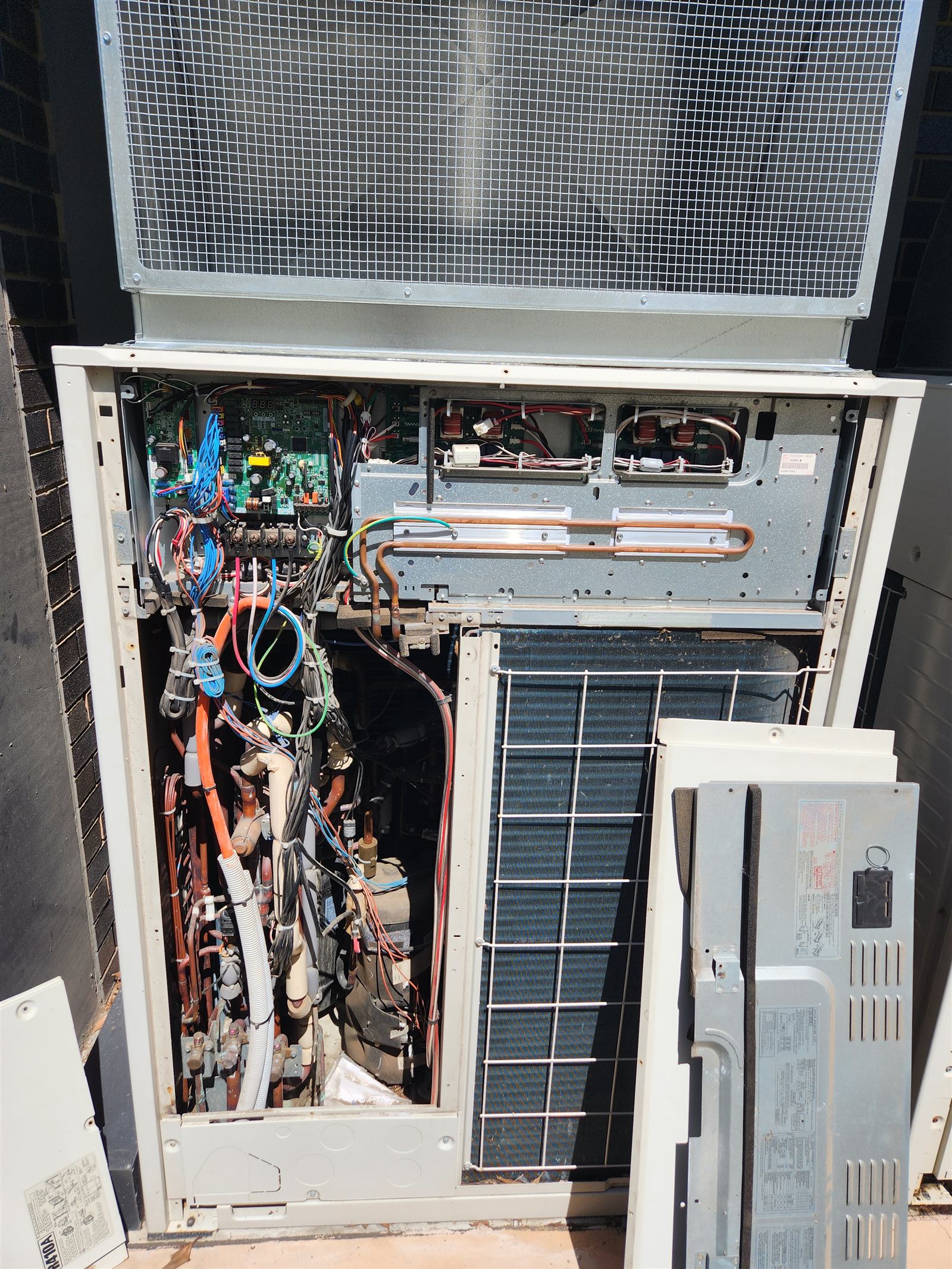 A commercial VRV outdoor unit opened up, showing its copper pipework and control boards